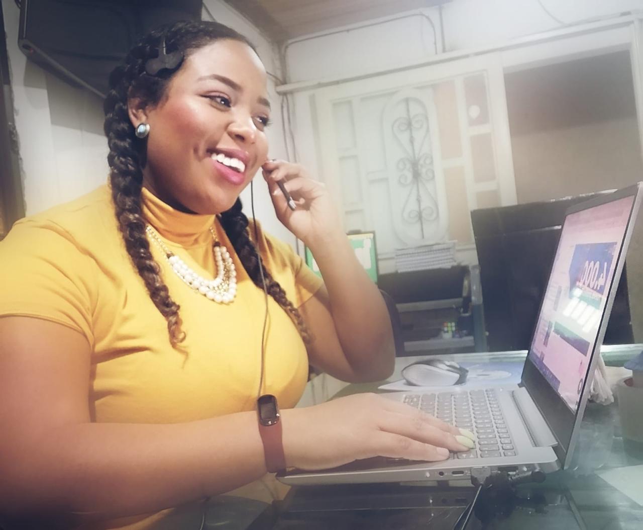 Mujer sonriente en computador atendiendo llamada