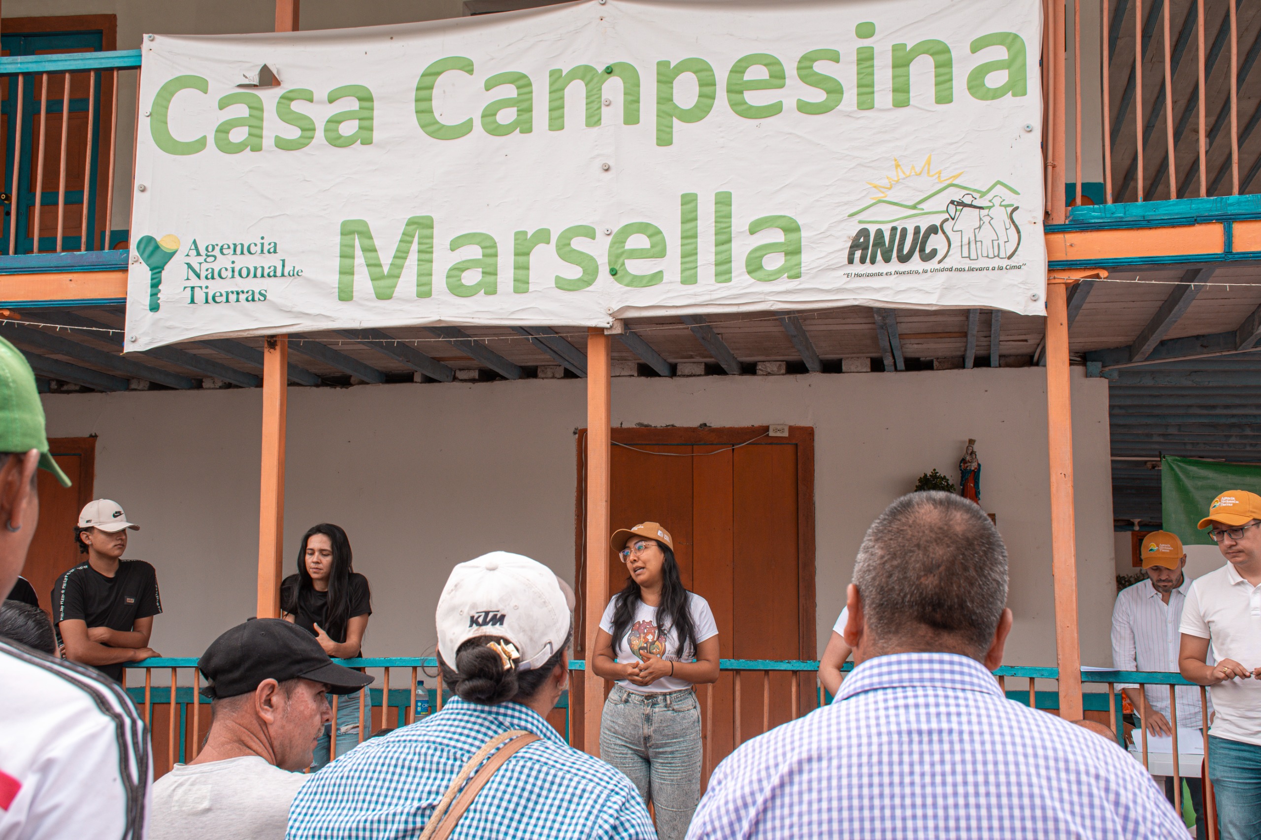 un-grupo-de-personas-parados-frente-a-una-bandera-que-dice-casa-campesina-la-marsella