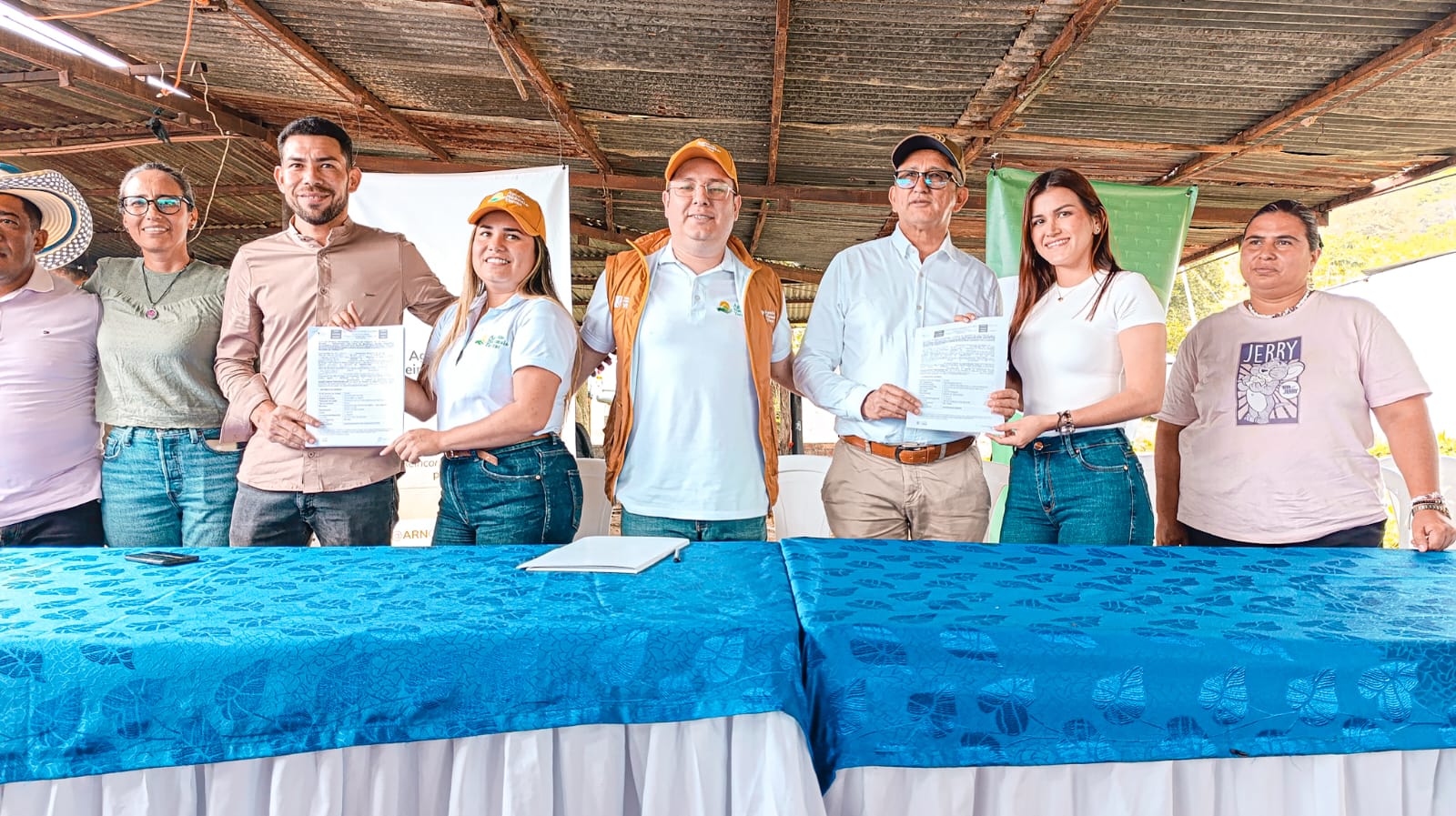 un-grupo-de-personas-de-pie-alrededor-de-una-mesa-con-un-mantel-azul