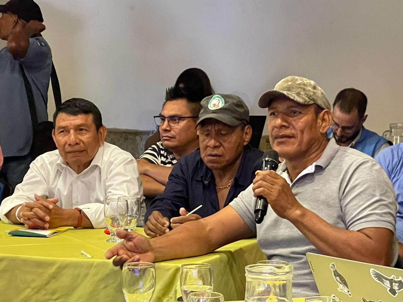 un-grupo-de-hombres-sentados-en-una-mesa-con-microfonos