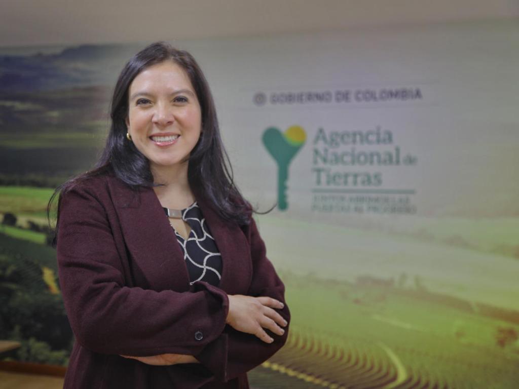 La Directora de la ANT, Myriam Martínez Cárdenas, aparece sola de brazos cruzados, de fondo el logo de la agencia. Anunciando que el Fondo de Tierras para la paz, alcanzó el 1 Millón de hectáreas.