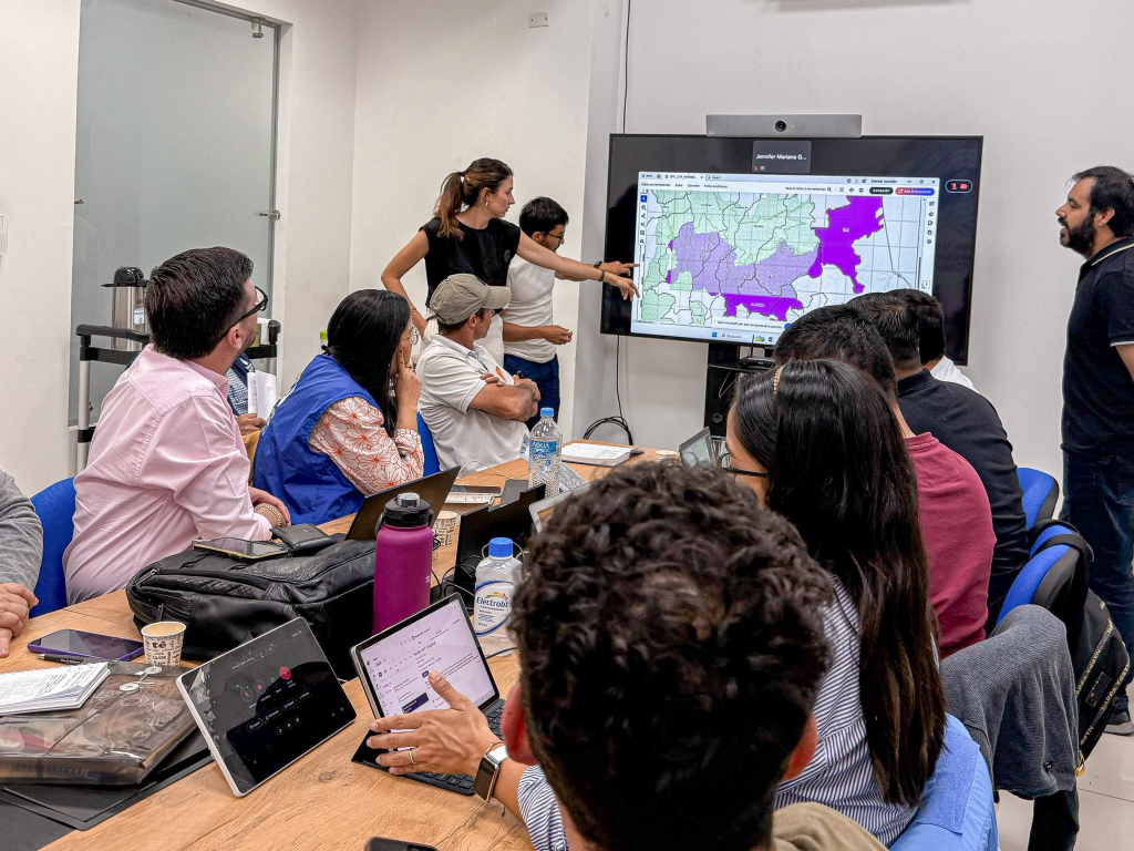 un-grupo-de-personas-sentadas-alrededor-de-una-mesa-con-una-computador