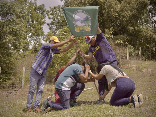 Campesinos sembrando simbolicamente una bandera de una asociación.