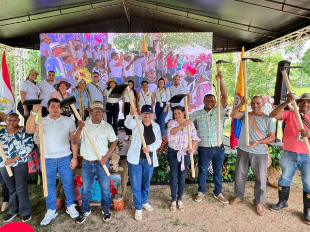 Beneficiarios de la entrega sosteniendo un asadón durante la ceremonia.