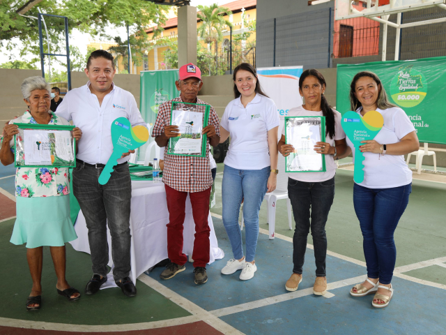 Campesinos de sucre mostrando título que recibieron junto a los funcionarios de la ANT