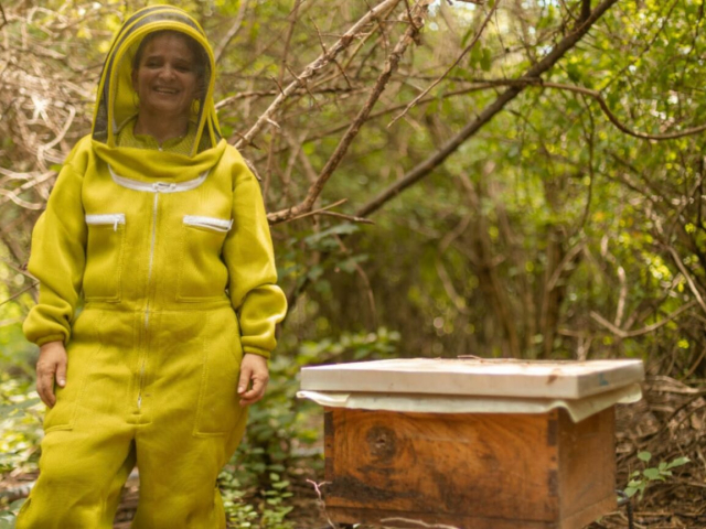 Mujer sonriendo con un traje de apicultor.