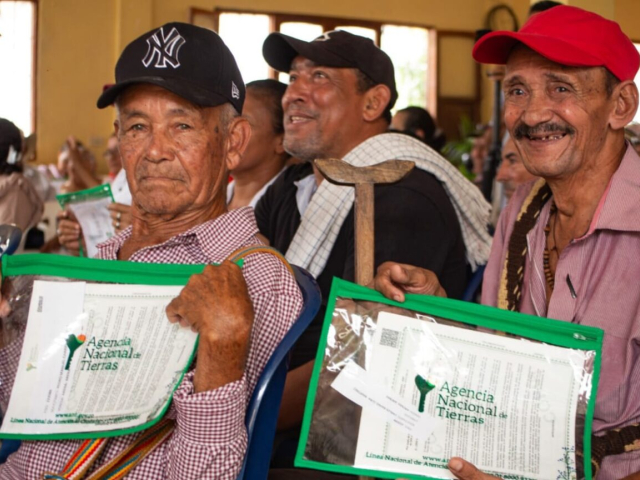 Dos señores campesinos sosteniendo sus títulos entregados por la ANT.