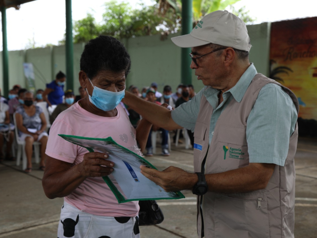 Campesina de monteria recibiendo título de propiedad por parte de funcionario 
