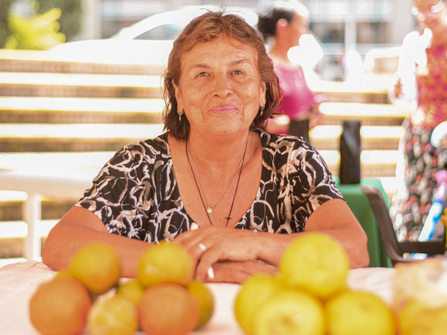 mujer-apoyandose-sobre-mesa-de-naranjas
