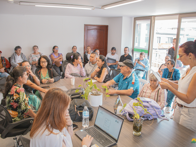 un-grupo-de-personas-sentadas-alrededor-de-una-mesa-con-computadoras