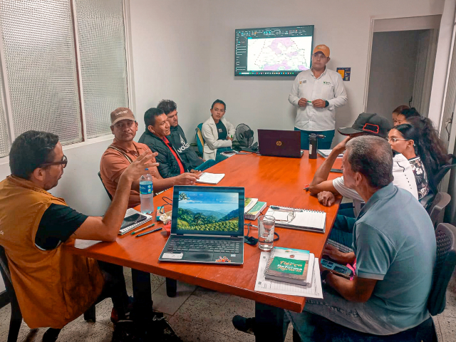 un-grupo-de-personas-sentadas-alrededor-de-una-mesa-con-una-computadora