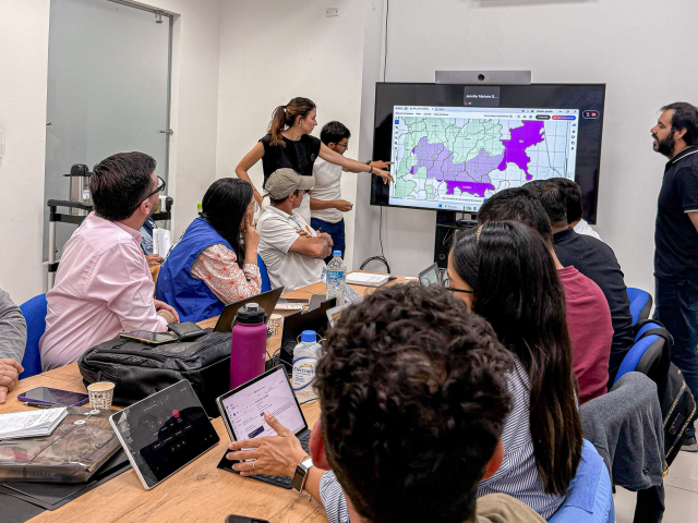 un-grupo-de-personas-sentadas-alrededor-de-una-mesa-con-una-computador