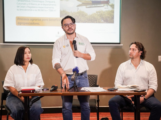 tres-personas-sentadas-en-una-mesa-con-una-pantalla-de-presentacion