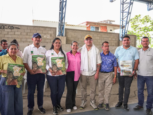 un-grupo-de-personas-parados-frente-a-un-edificio-con-titulos-de-tierras-en-las-manos