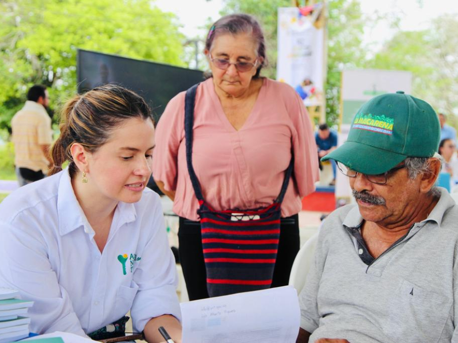 Funcionario}a de la ANT explicando algo a una pareja asistente a la feria