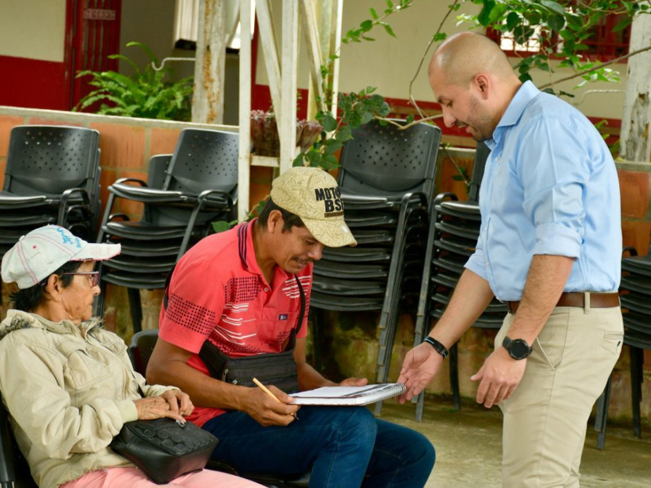 Funcionario haciendo entrega de título a dos campesinos.