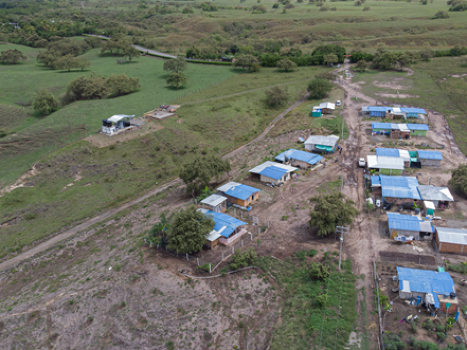 Fotografía tomada desde el cielo del pueblo de Patía Cauca. En ella se observan varias casas con techo color azul y a su alrededor terreno con pasto verde, árboles y partes de caminos destapados.