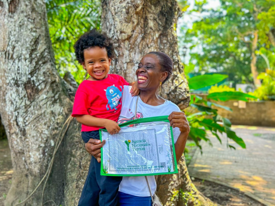 Mujer afro sonriendo con su titulo y su hijo en brazos.