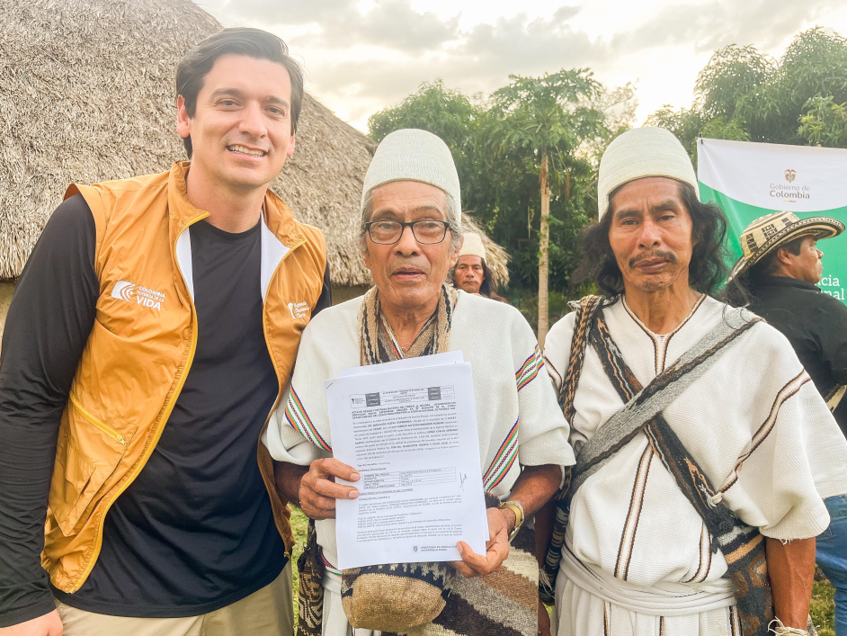 dos-hombres-y-una-mujer-sosteniendo-papeles-frente-a-una-cabana