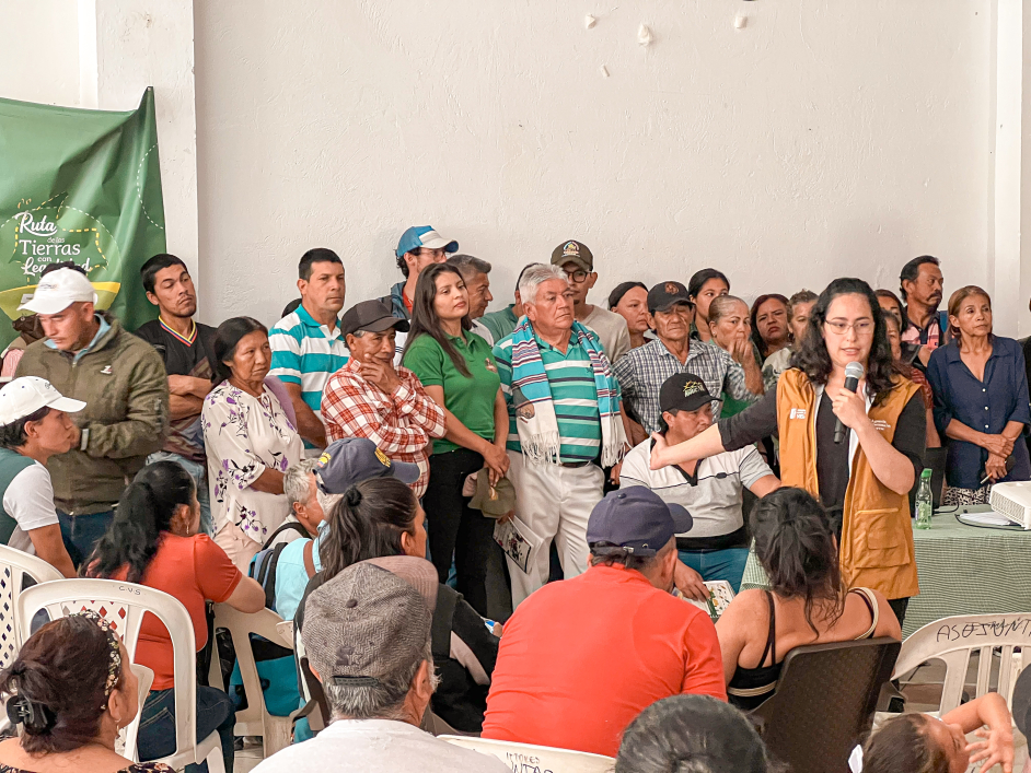 un-grupo-de-personas-de-pie-alrededor-de-una-mesa-con-una-mujer-hablan