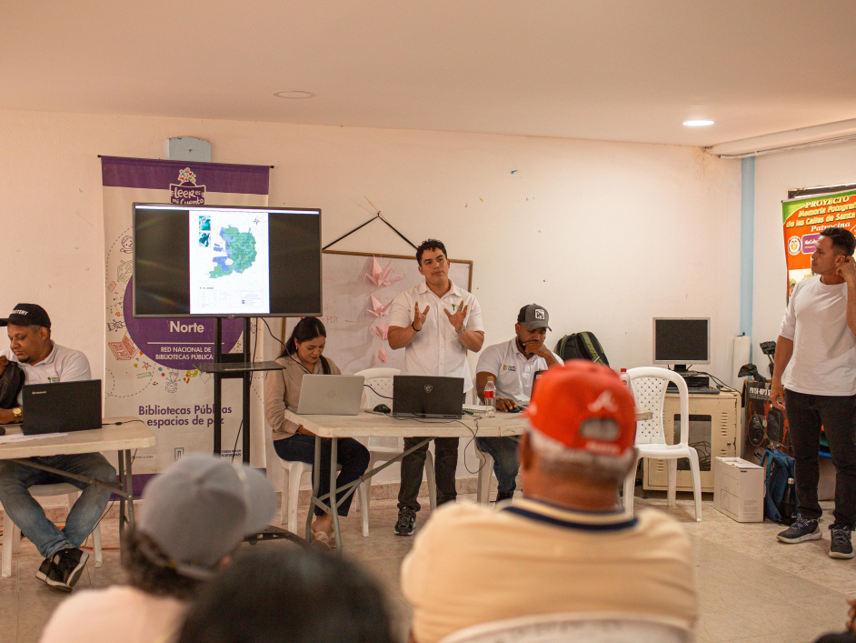 un-grupo-de-personas-sentadas-alrededor-de-una-mesa-con-un-hombre-de-pie