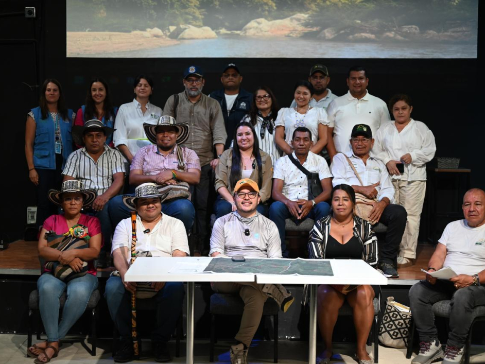 un-grupo-de-personas-sentadas-junto-director-ant-en-una-mesa-con-una-pantalla-de-proyecto