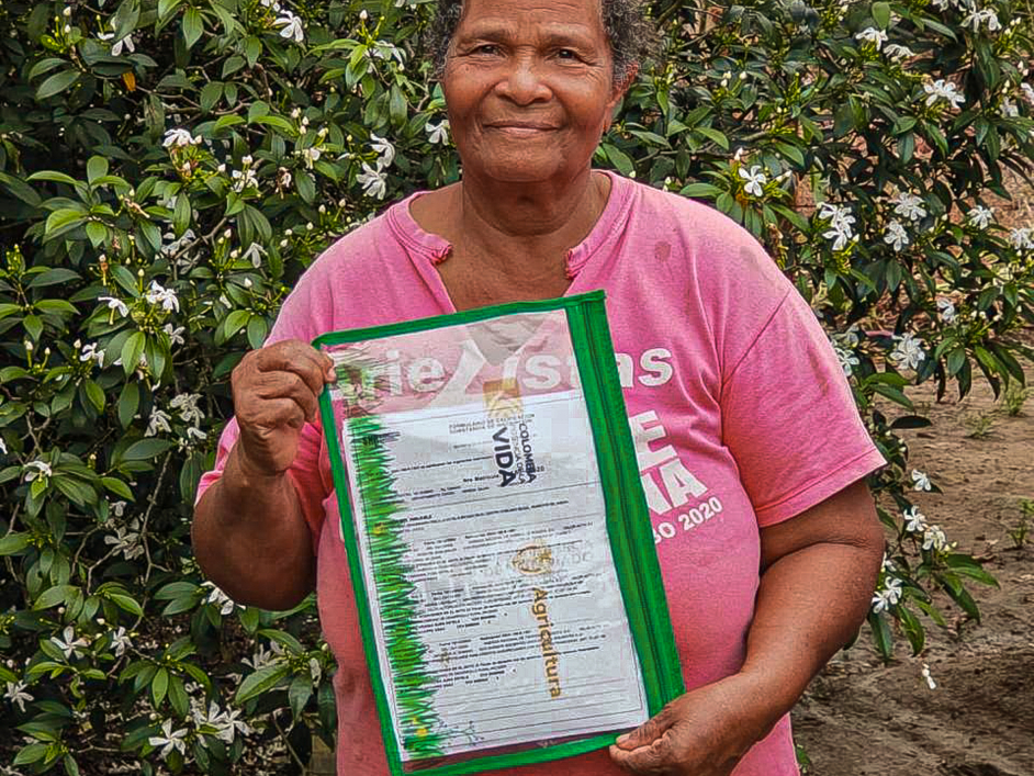 una-mujer-que-sostiene-un-certificado-frente-a-los-arbustos