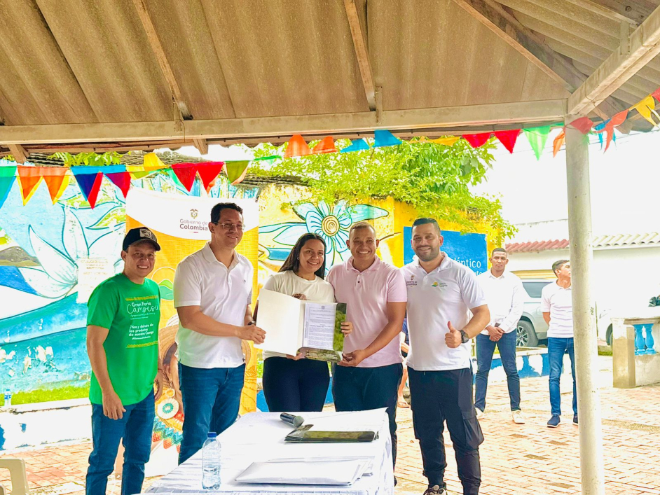 un-grupo-de-personas-paradas-alrededor-de-una-mesa-con-un-certificado