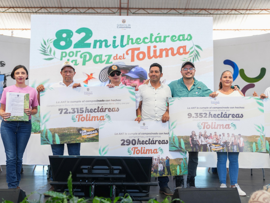 Grupo de personas en tarima en compañia del presidente Pretro mostrando en carteles grandes cifras sobre hectareas recuperadas y predios.
